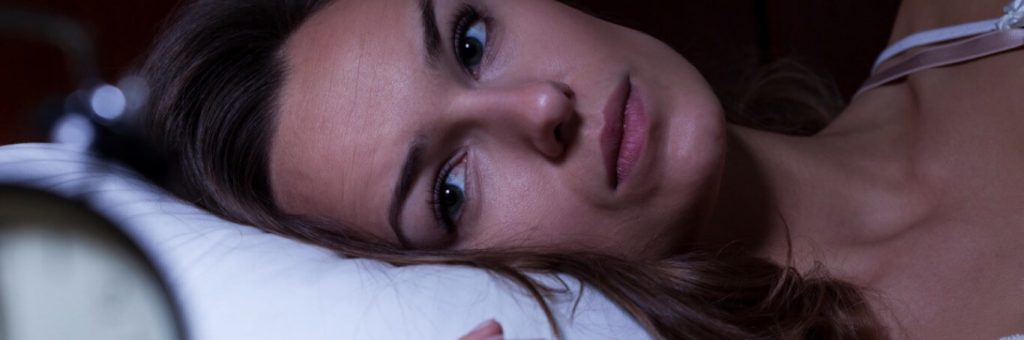 woman stays awake at night having trouble of falling asleep