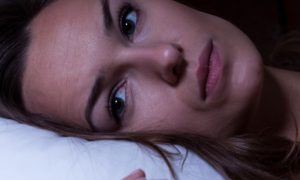 woman stays awake at night having trouble of falling asleep