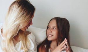 woman sits on bed talking to daughter