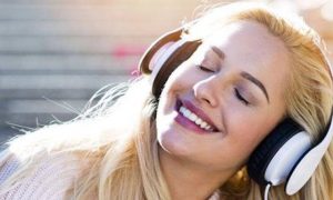 woman wears headphones listening to music happily smiling