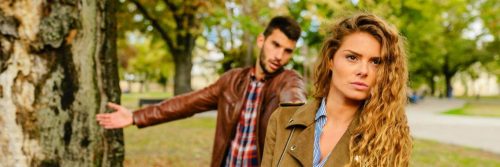 couple haves conflict in public park man trying to explain while woman angrily waking away