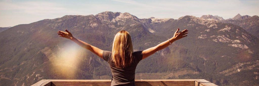 woman stands looking at mountain gratitude life in blue sunny sky