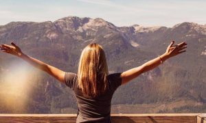 woman stands looking at mountain gratitude life in blue sunny sky