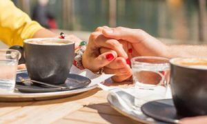 hands holding beside two coffee cups two glasses of water