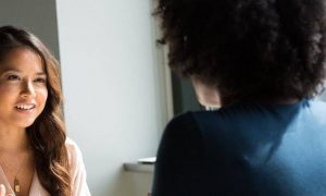 woman happily talks discussed with curly hair woman in office