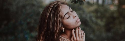 woman closed eyes hands under chin focuses on breathing immersing into nature
