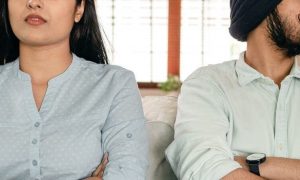 couple sits on white couch in living room not talking to each other