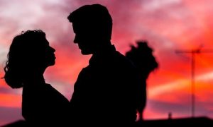 couple shadow hugging looking at each other in dark red sky