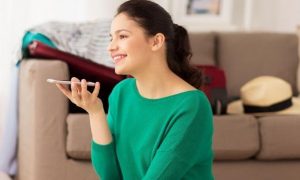 woman sitting beside couch talking on phone in living room