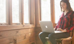 woman sits alone busy working on apple macbook