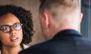 curly black hair woman sits in coffee shop talking to college