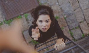 woman about to climb stair raises hand asking for help support