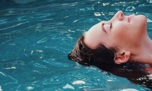 woman swimming backstroke relaxing in pool