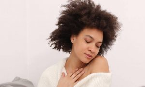 curly black hair woman closed eyes hand on chest feeling loved herself