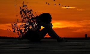 woman shadow sadly sits crying in red sunset sky
