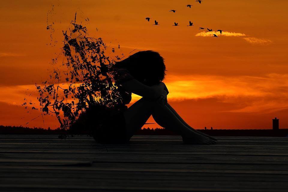 woman shadow sadly sits crying in red sunset sky
