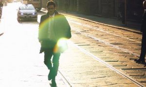 businessman walks alone on street beside railway