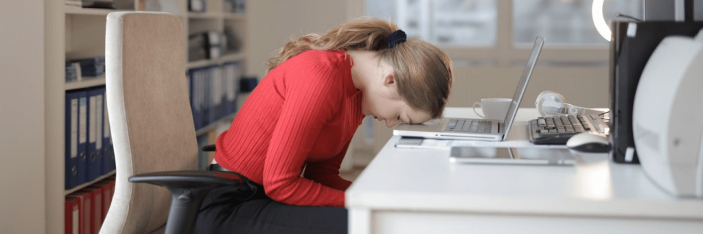 woman head on laptop distressed feeling tired in office room