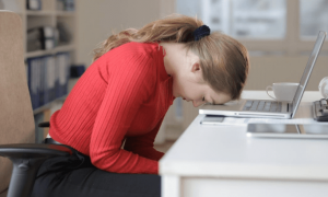 woman head on laptop distressed feeling tired in office room