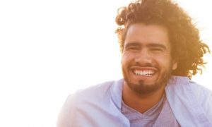 curly hair man smiles in sunny sky