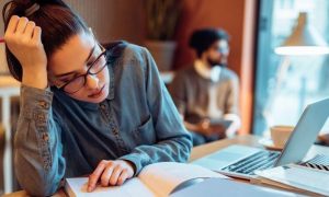 woman sits in coffee tiredly stressed studying