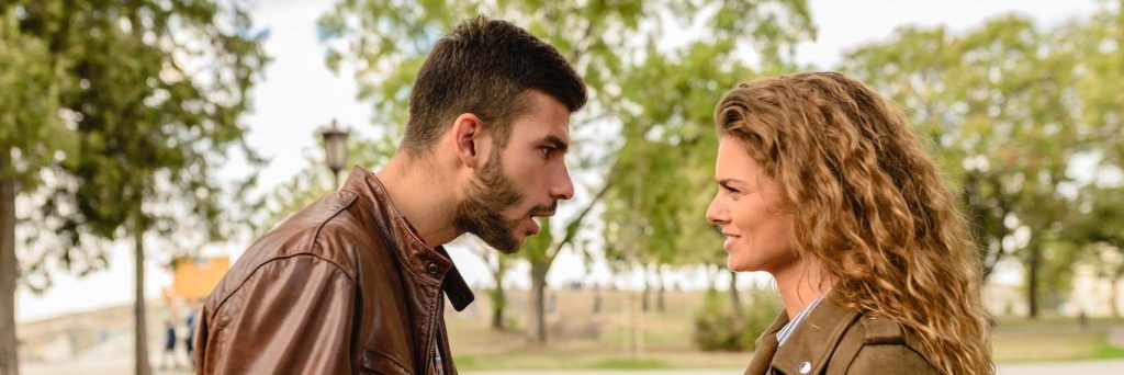 couple argues in forest man trying to explain while woman angrily listening looking at him