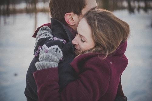 A couple hugging with snow in the background